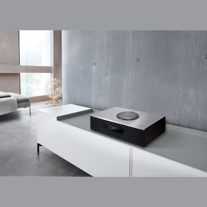 Technics SC-C70MK2 Kompaktanlage Silber Lifestyle auf weissem Sideboard vor Betonwand