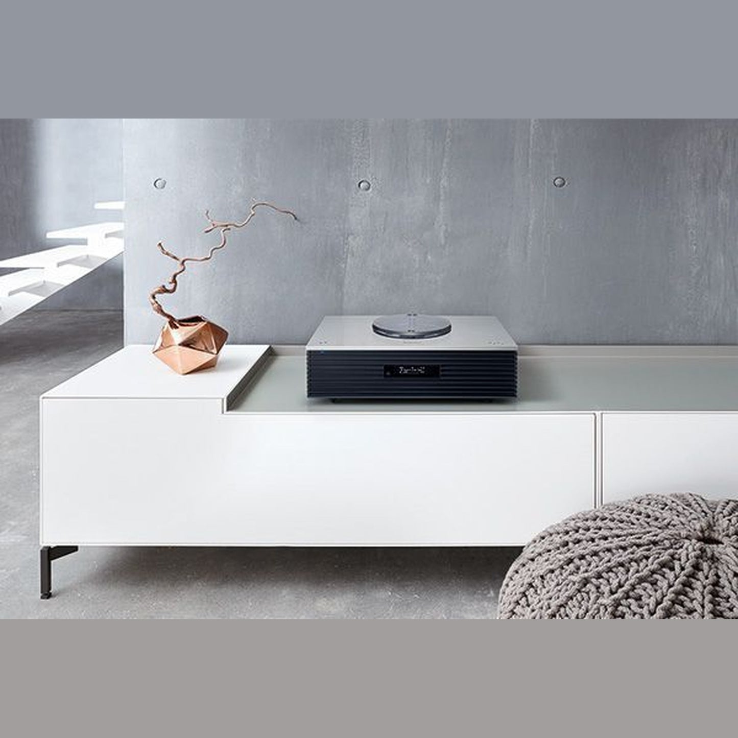 Technics SC-C70MK2 Kompaktanlage Silber Lifestyle auf weissem Sideboard mit Deko-Zweig und Strickpouf