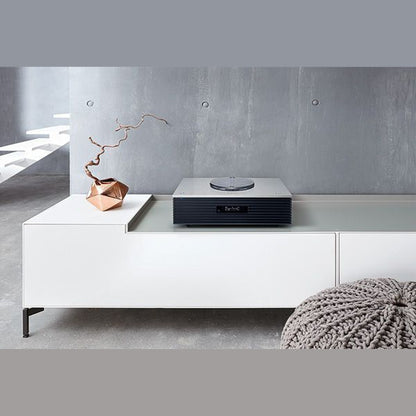 Technics SC-C70MK2 Kompaktanlage Silber Lifestyle auf weissem Sideboard mit Deko-Zweig und Strickpouf