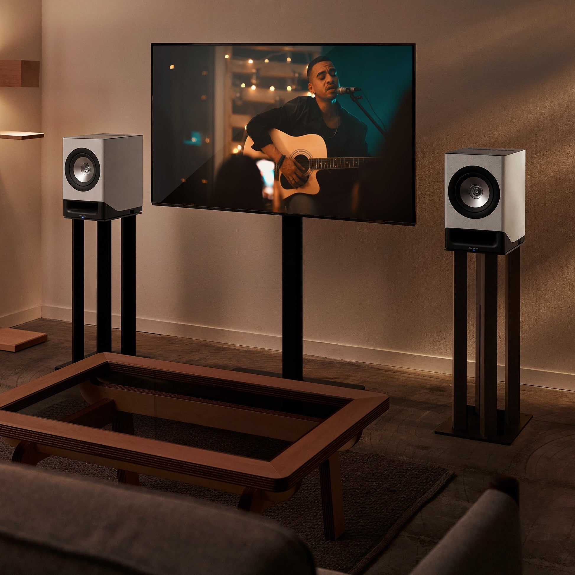 Technics SC-CX700 Streaming-Lautsprecher Grau Lifestyle auf Standfüssen links und rechts vom Fernseher
