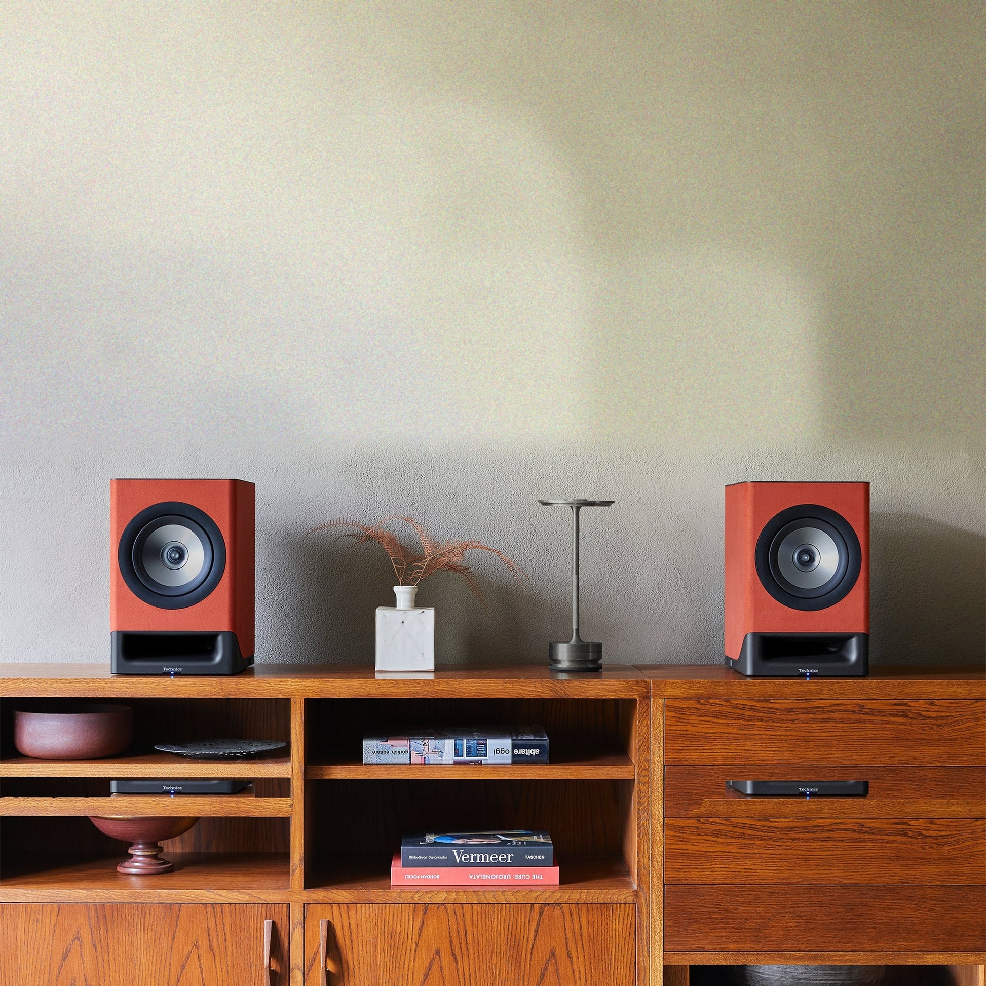 Technics SC-CX700 Streaming-Lautsprecher Terracotta Lifestyle auf Teak-Sideboard mit Vase und Tischleuchte