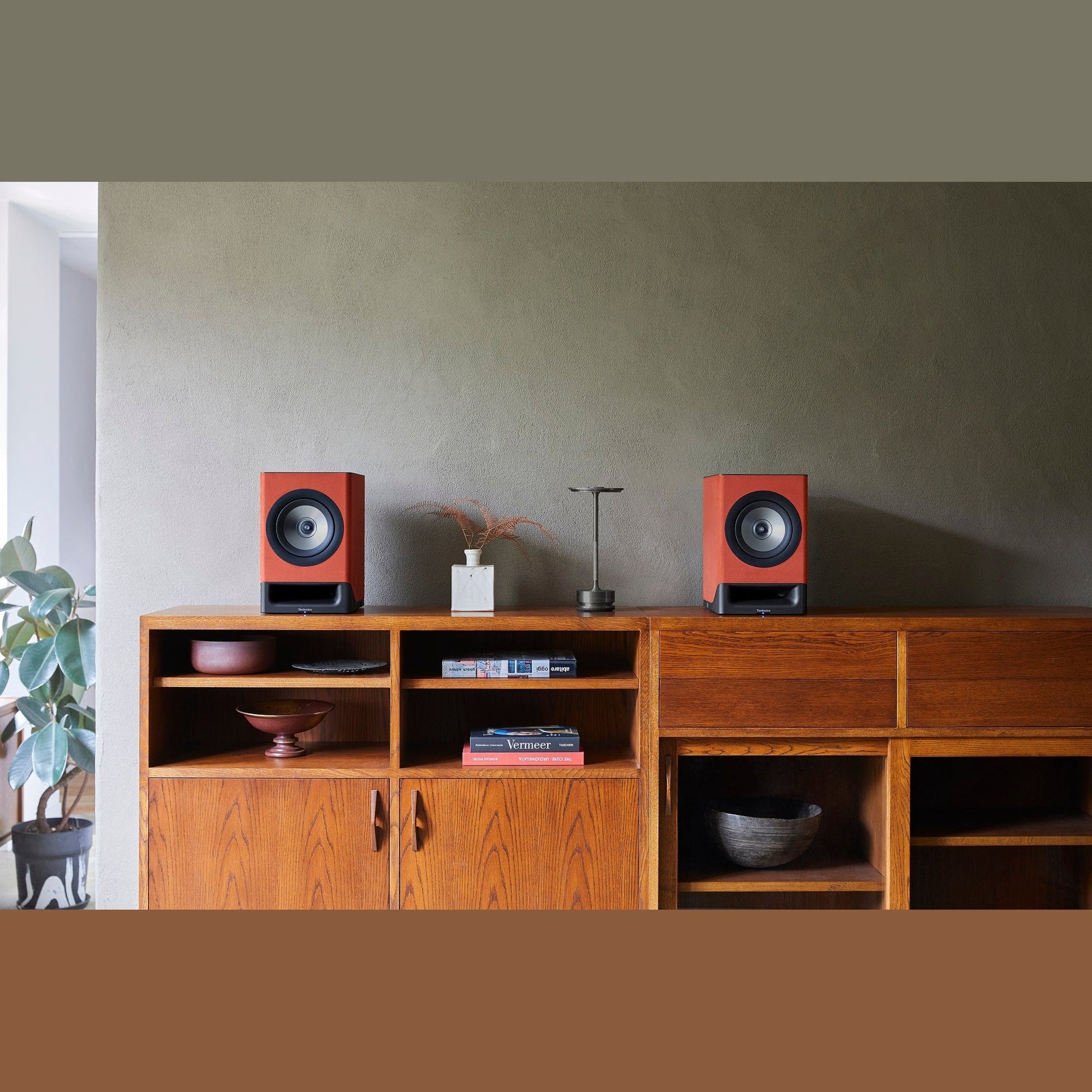 Technics SC-CX700 Streaming-Lautsprecher Terracotta Lifestyle paarweise auf Teak-Sideboard vor olivgrüner Wand