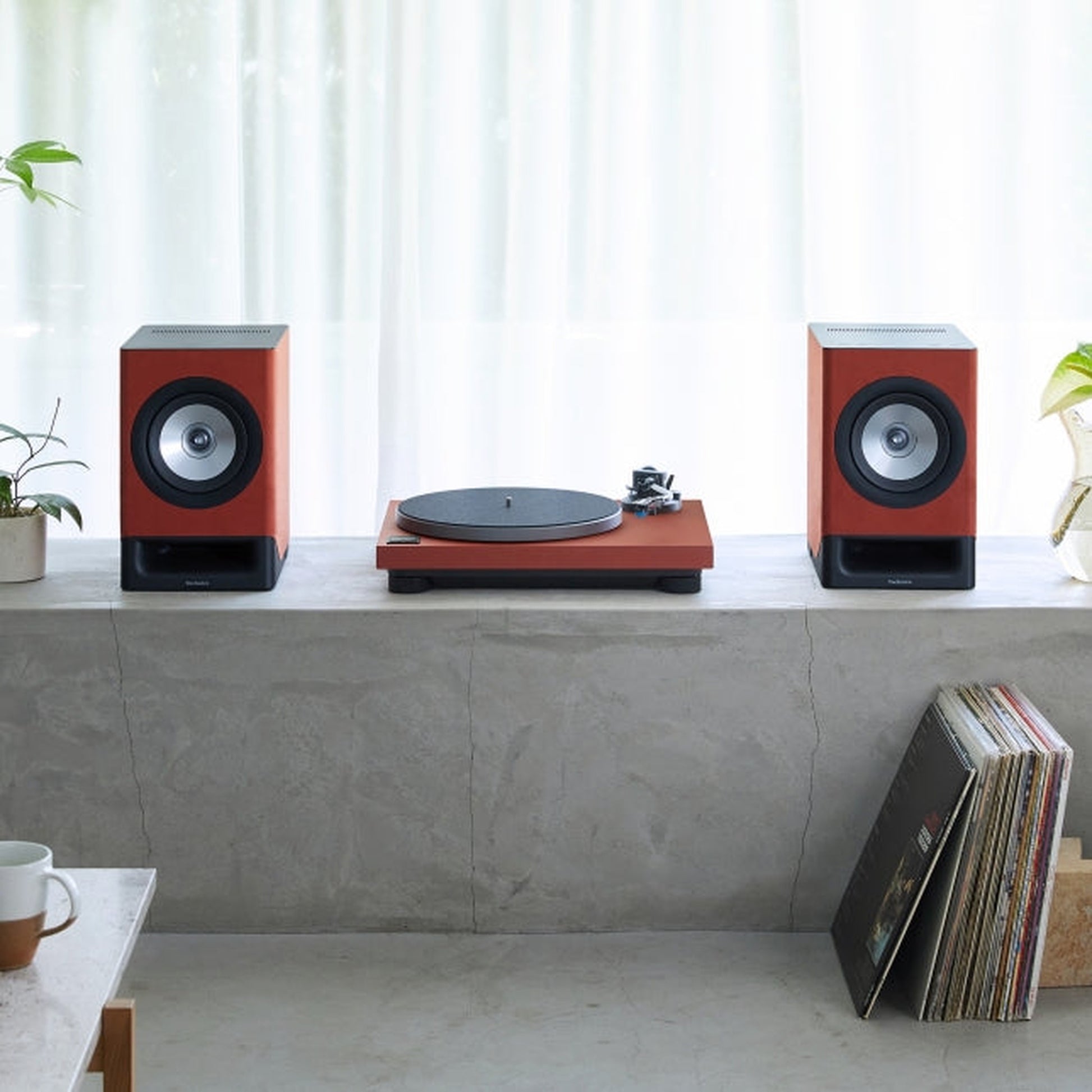 Technics SL-40CBT + SC-CX700 HiFi-Set Terracotta Lifestyle, Set auf einem Betonsims im Wohnraum mit Schallplattensammlung