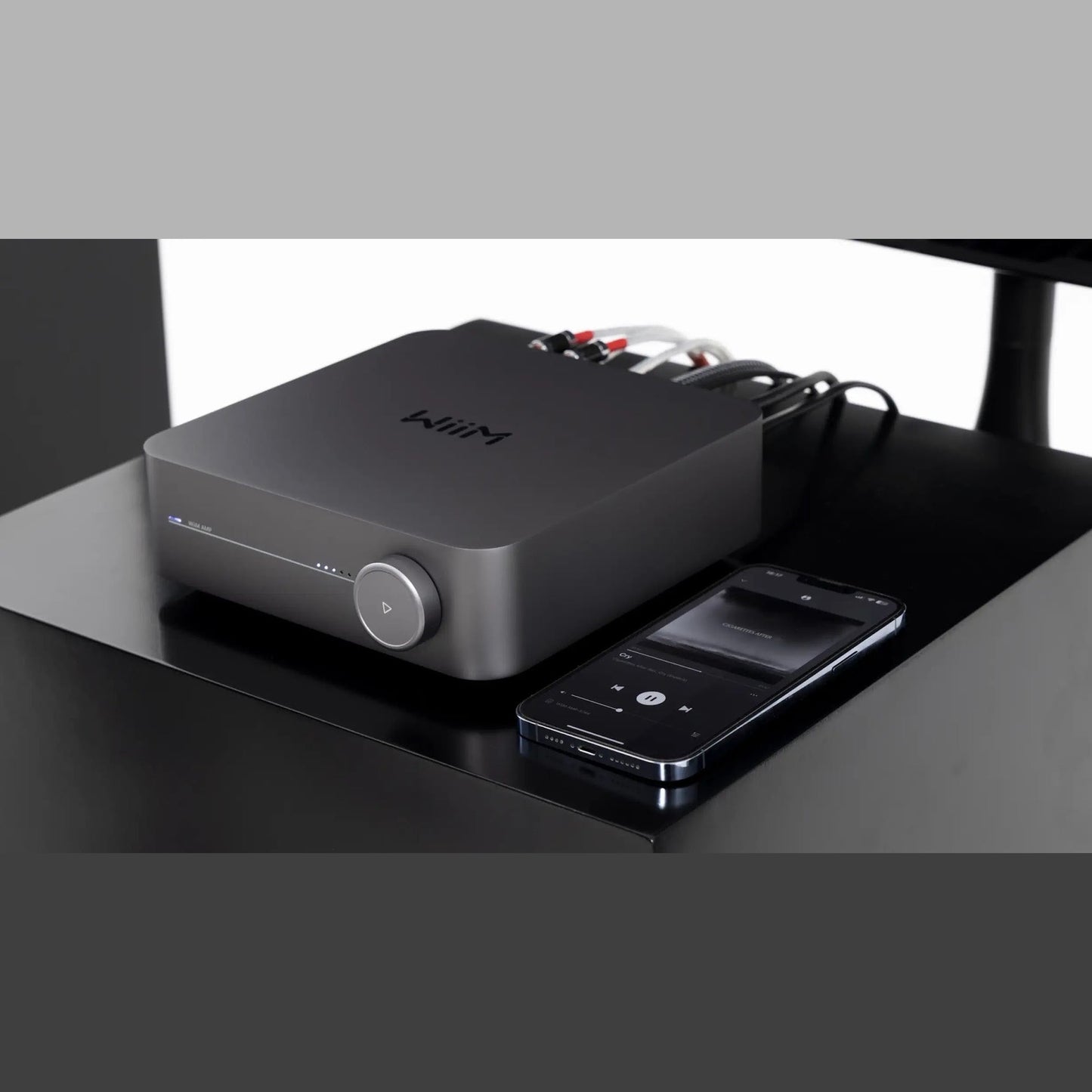 WiiM Amp Streaming-Verstärker Space Gray Lifestyle 3 auf dem Schreibtisch mit Smartphone