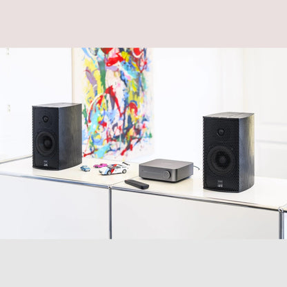 WiiM Amp Streaming-Verstärker Space Gray Lifestyle auf Sideboard mit Kompaktlautsprechern