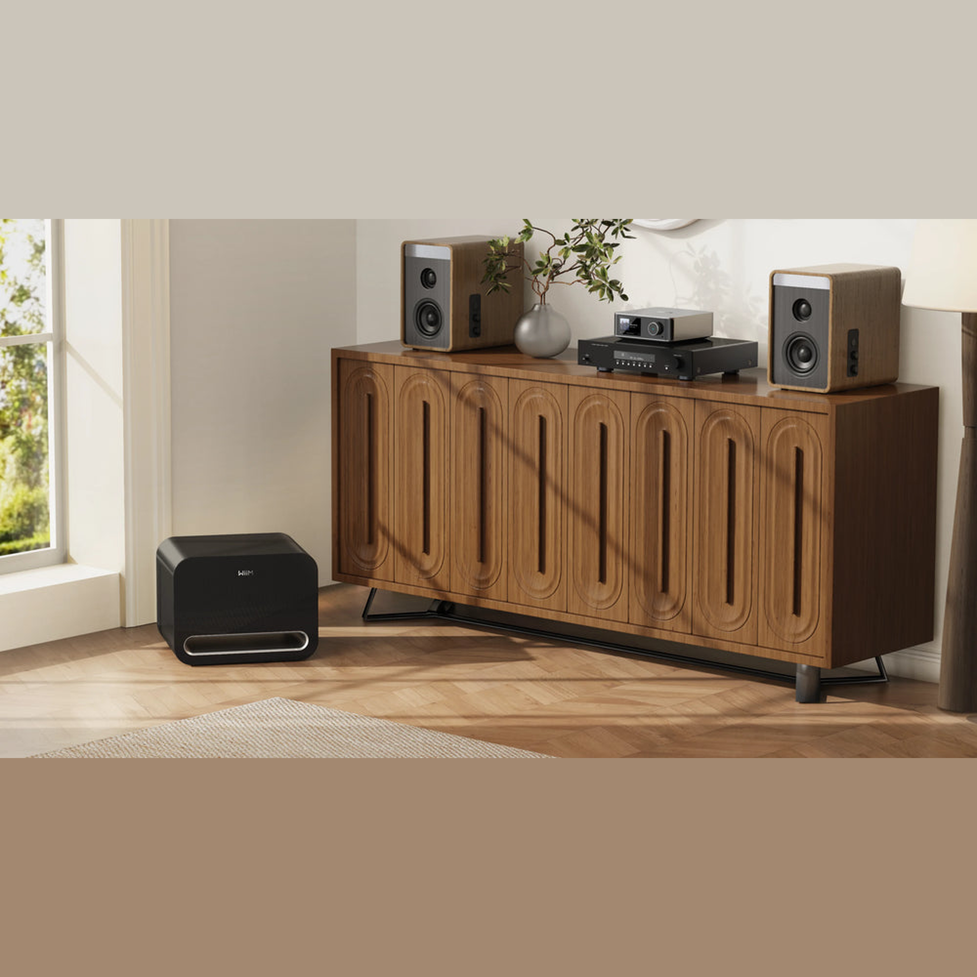 WiiM Sub Pro Wireless-Subwoofer Schwarz Lifestyle 2 im Wohnzimmer neben dem Sideboard