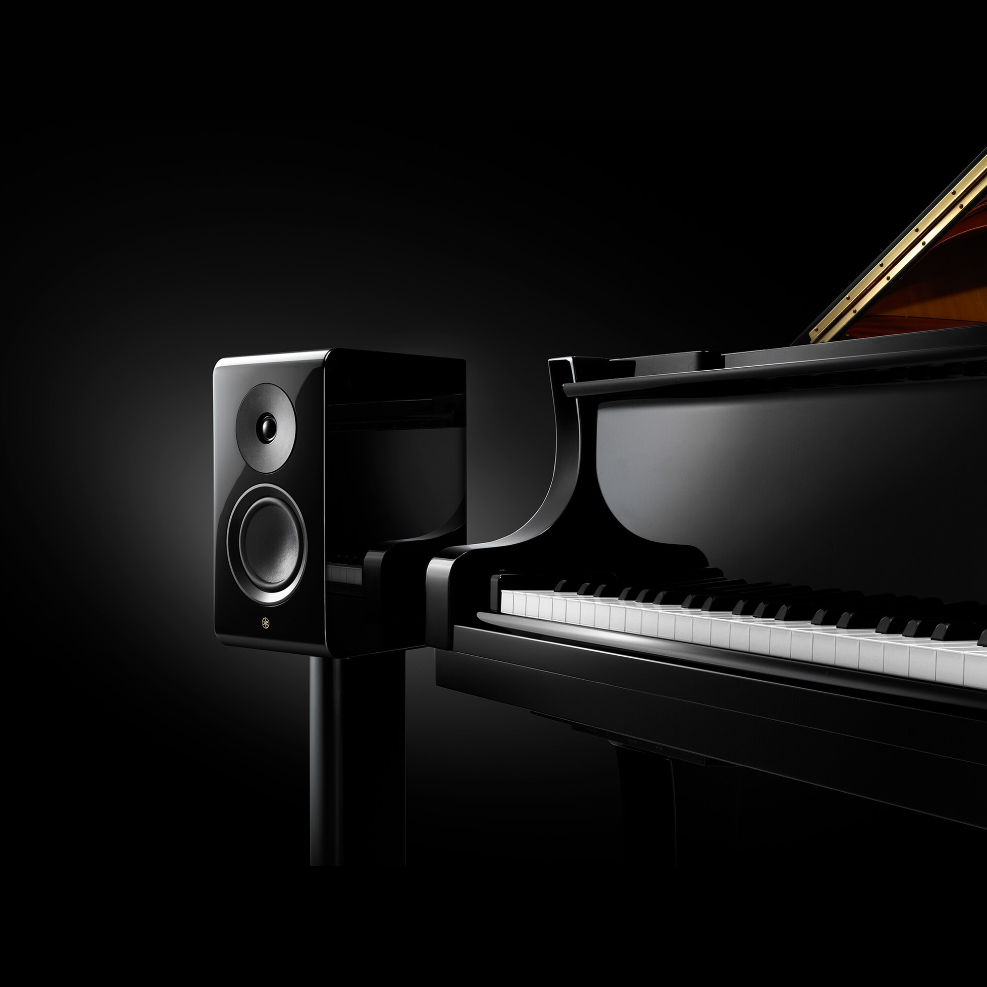 Yamaha NS-600A Regallautsprecher Klavierlack Lifestyle auf Ständer neben einem Konzertflügel