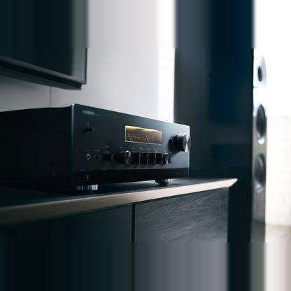 Yamaha R-N2000A Netzwerk-Receiver Schwarz Lifestyle auf Sideboard neben einem Standlautsprecher