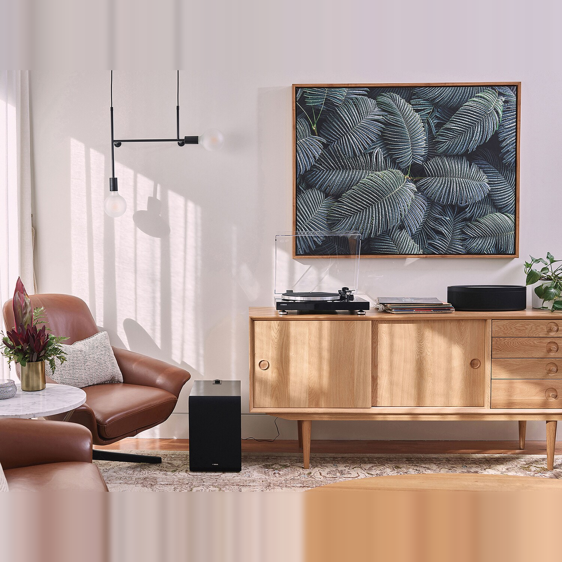 Yamaha TT-N503 MusicCast-Plattenspieler Schwarz Lifestyle auf Sideboard mit Subwoofer und Sessel